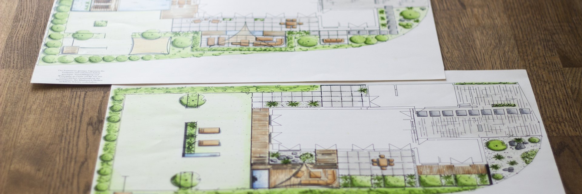 Zwei handkolorierte Gartenentw&uuml;rfe auf einem Holztisch, mit Terrassenfl&auml;chen, Wasserbecken, Pflanzfl&auml;chen und Baumsymbolen