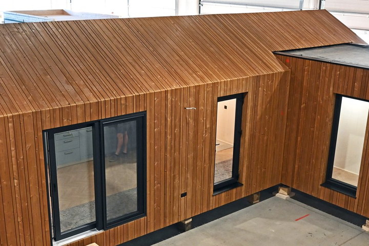 Ausgef&uuml;hrtes CLT-Modulhaus in der Fertigung: Holzschalung und dunkle Fensterrahmen