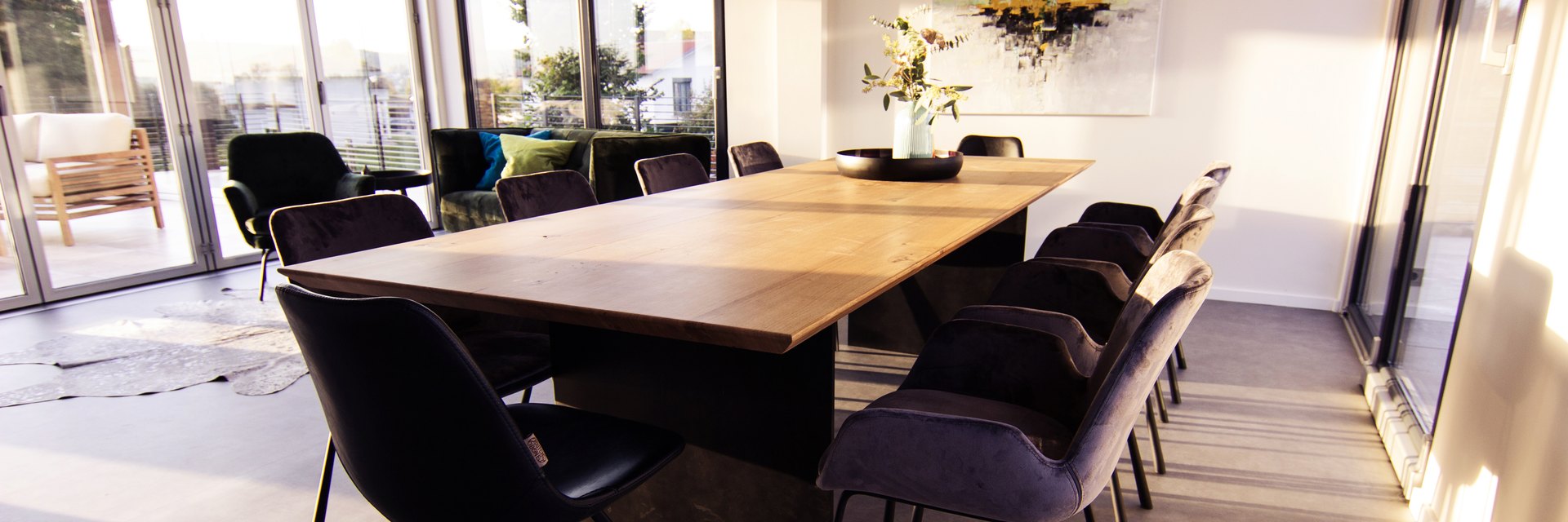 LE ConferenceTable aus massiver Eiche mit dunklem Mittelfuss und zehn Polsterstuehlen im Konferenzraum der LE Lounge