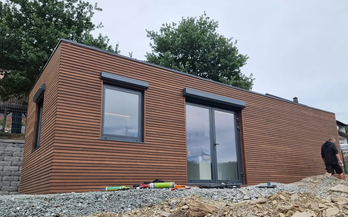 Das fertig aufgestellte MicroHouse mit horizontaler Holzschalung, Fenster und zweiflügeliger Glastür