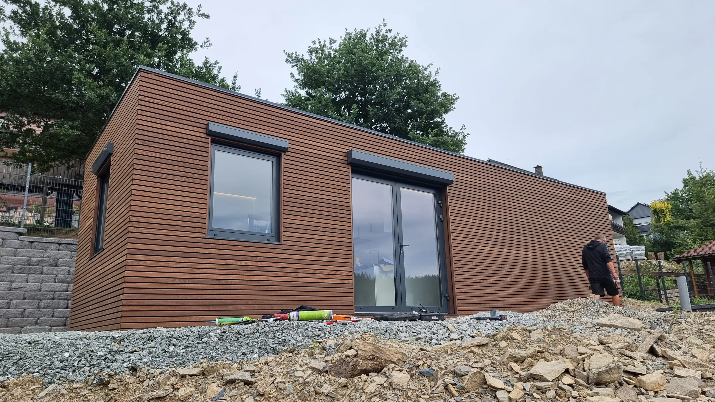 Das fertig aufgestellte MicroHouse mit horizontaler Holzschalung, Fenster und zweiflügeliger Glastür