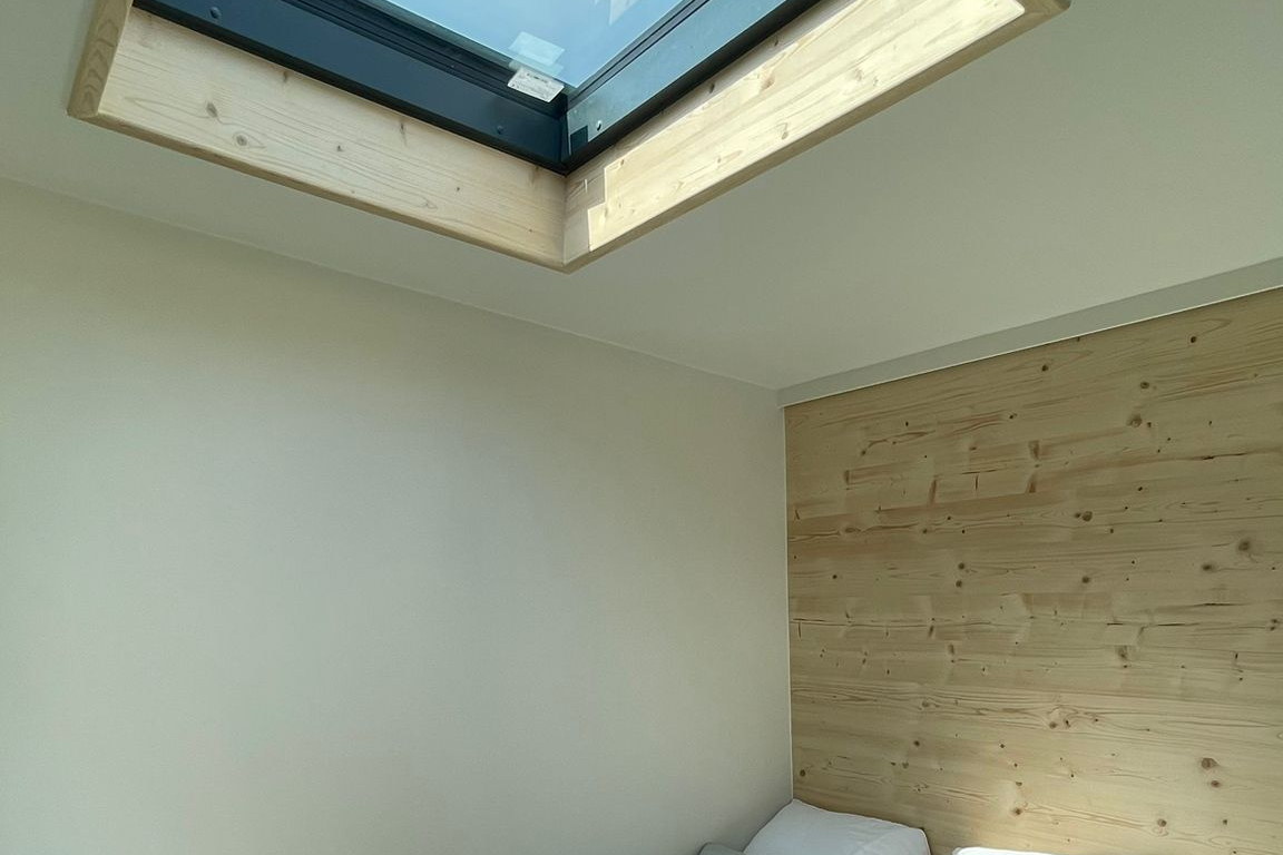Dachfenster im Moonwalker-Modul: großes Oberlicht in der Schräge über dem Schlafbereich, Holzlaibung und Holzwand