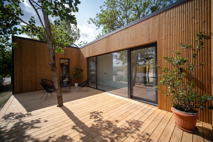 Holzverkleideter Innenhof des LE ModulHaus 100 m&sup2; mit Terrasse und raumhoher Schiebet&uuml;r