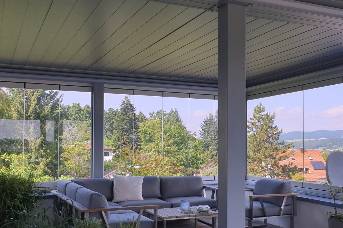 Ausgef&uuml;hrtes Lamellendach &uuml;ber einer Dachterrasse: geschlossene Aluminium-Lamellen als Decke, ringsum rahmenlose Glasschiebeelemente, Loungem&ouml;bel und Pflanzk&uuml;bel