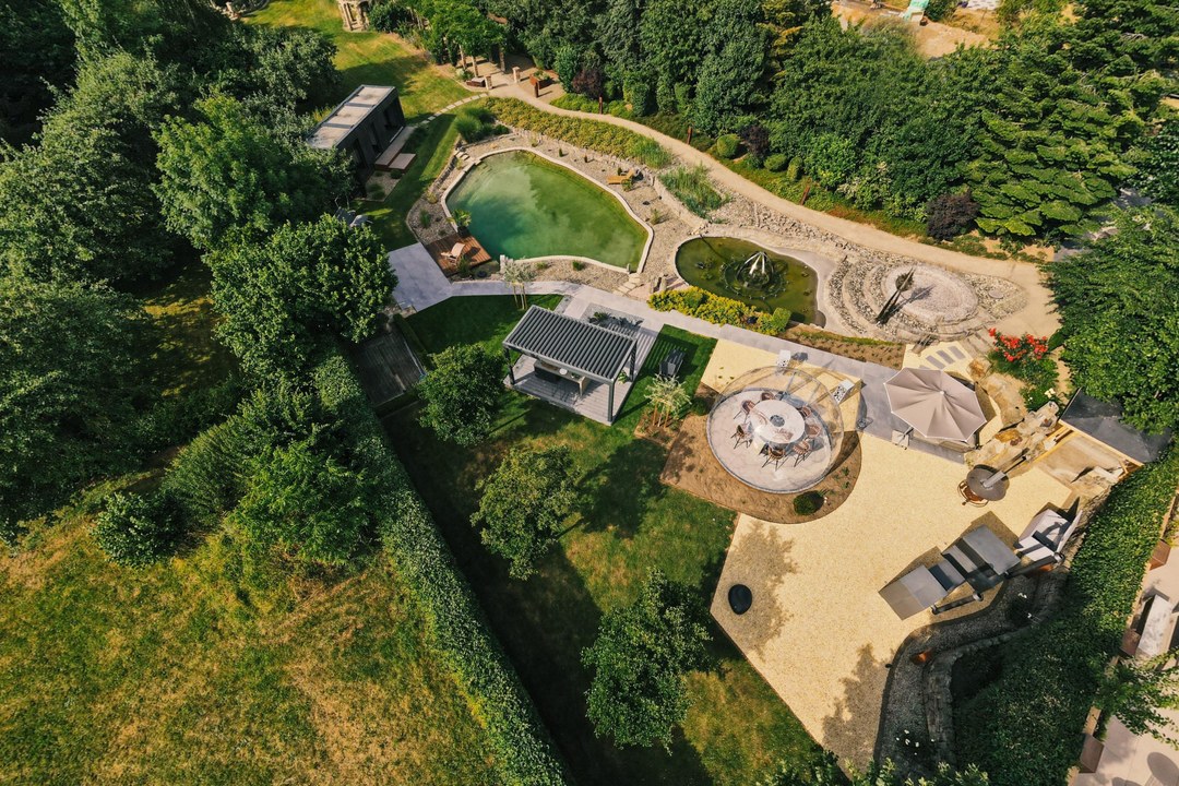 Luftbild des LE Außenshowrooms mit Naturbadeteich, Glaspavillon, Pergola und Kiesterrassen