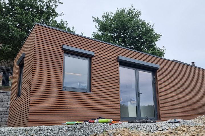 Fertiges LE MicroHouse mit horizontaler Thermoholz-Fassade auf der vorbereiteten Gründung