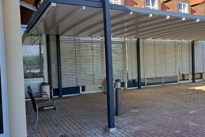 Freistehende Pergola mit gespanntem Textildach über der Terrasse eines Gastronomiebetriebs