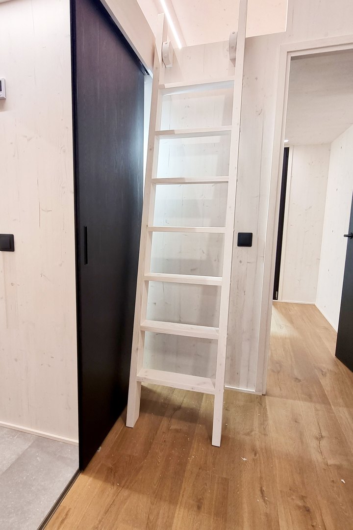 Flur eines ausgef&uuml;hrten LE TinyHouse mit Eichendielen, dunkler Schiebet&uuml;r und Leiter zur Schlafgalerie